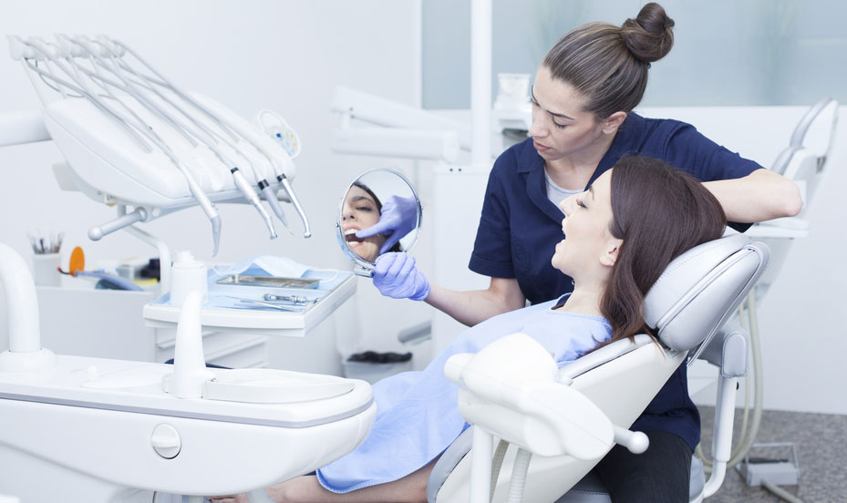 patient looking at her teeth in the mirrow after cosmetic procedure