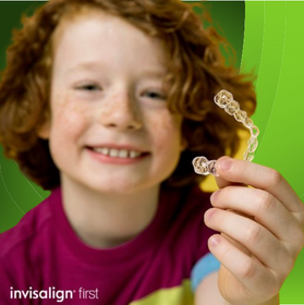 Young boy holding his Invisalign First® clear aligners on his hands
